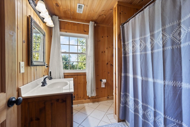 bathroom with wood walls, wooden ceiling, tile patterned flooring, and vanity