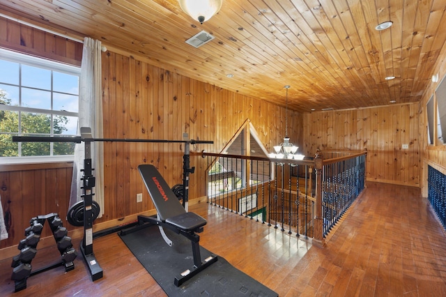 workout area with a notable chandelier, wood walls, hardwood / wood-style floors, and wooden ceiling