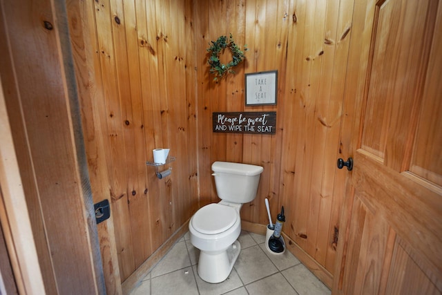 bathroom with tile patterned flooring, wood walls, and toilet