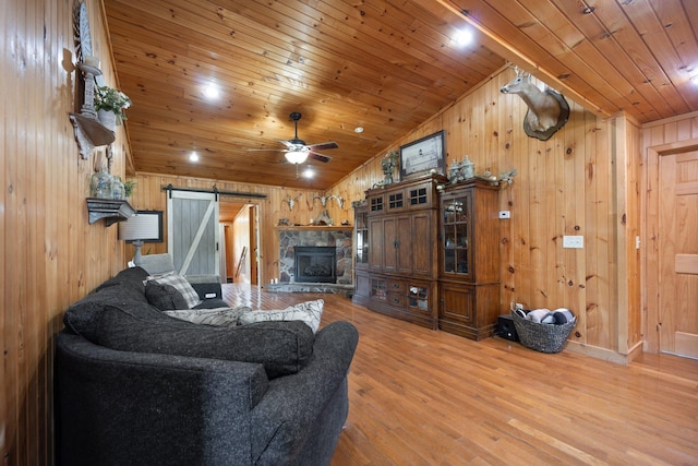 living room with lofted ceiling, wooden walls, wood-type flooring, wooden ceiling, and a barn door