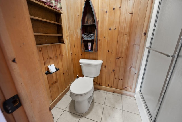 bathroom featuring wooden walls, tile patterned flooring, toilet, and a shower with door