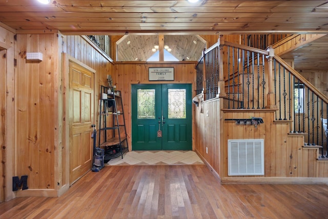 foyer with french doors, wood ceiling, hardwood / wood-style flooring, vaulted ceiling, and wood walls