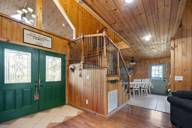 entryway with wood walls, wood-type flooring, wooden ceiling, and ceiling fan