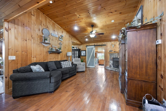 living room with a barn door, wood walls, ceiling fan, wood-type flooring, and wood ceiling