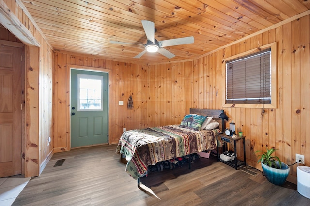 bedroom featuring ceiling fan, wood walls, wooden ceiling, and wood-type flooring