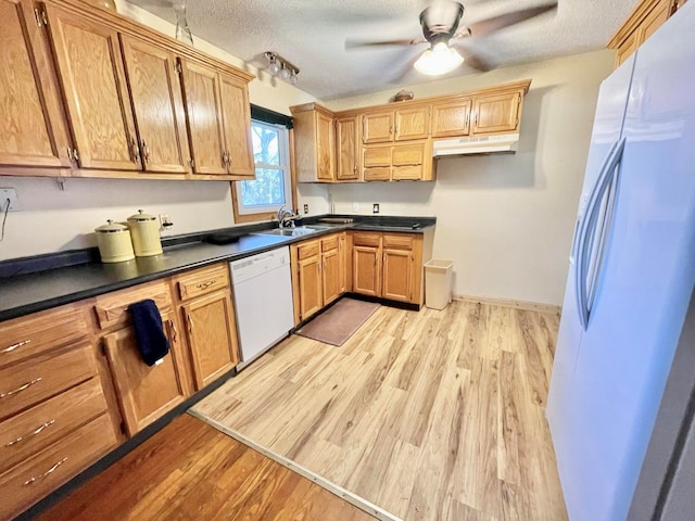 kitchen featuring a textured ceiling, light wood-type flooring, and white appliances