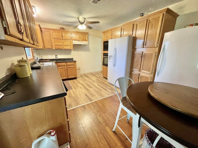 kitchen with ceiling fan, light hardwood / wood-style flooring, sink, black appliances, and a textured ceiling