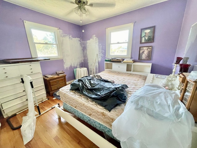 bedroom featuring ceiling fan, a textured ceiling, and light wood-type flooring