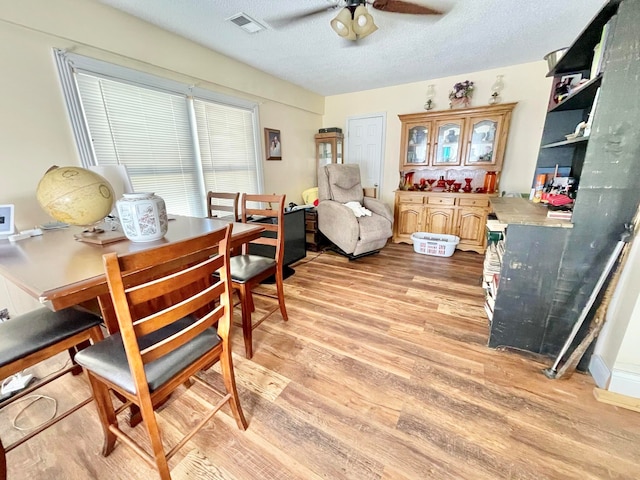 dining area featuring ceiling fan, a textured ceiling, and light wood-type flooring