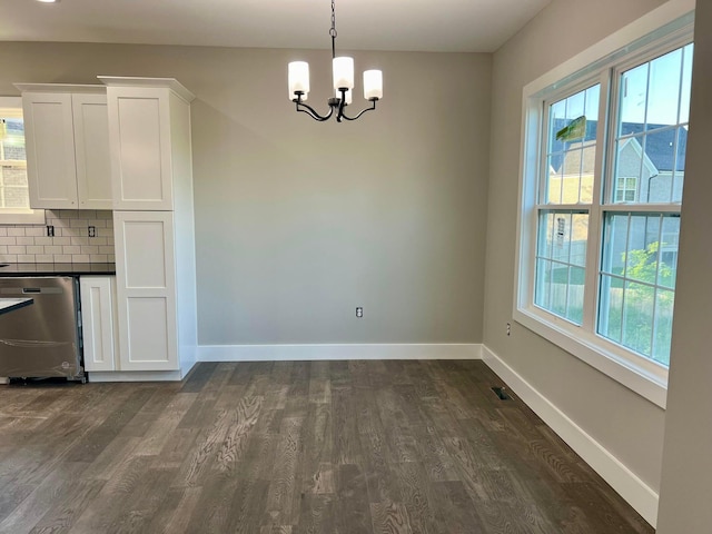 unfurnished dining area with dark wood-type flooring and a chandelier