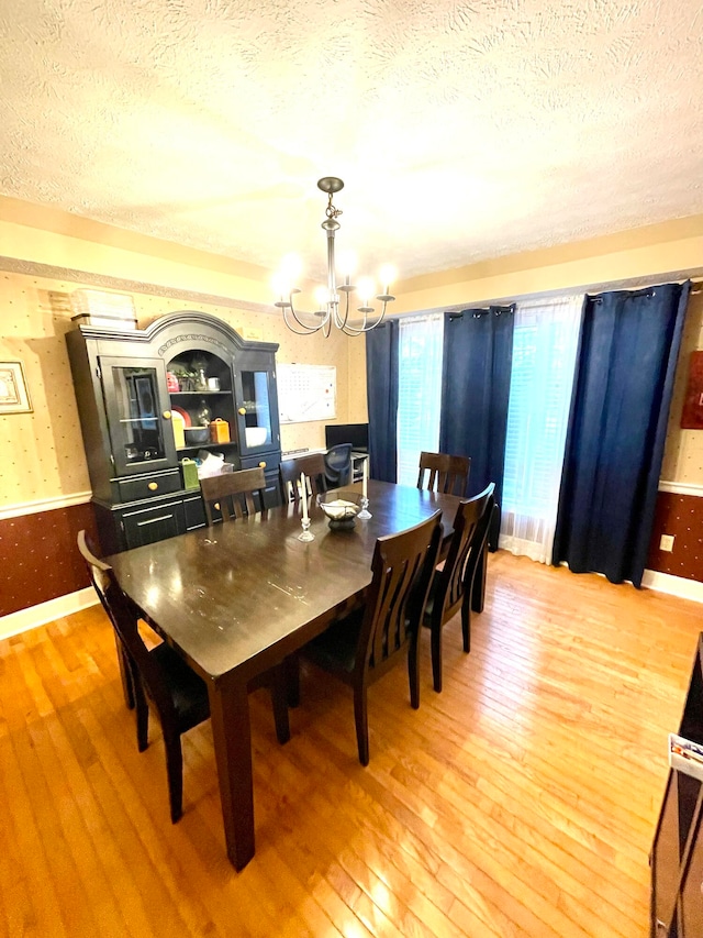 dining space featuring a notable chandelier, a textured ceiling, and hardwood / wood-style floors