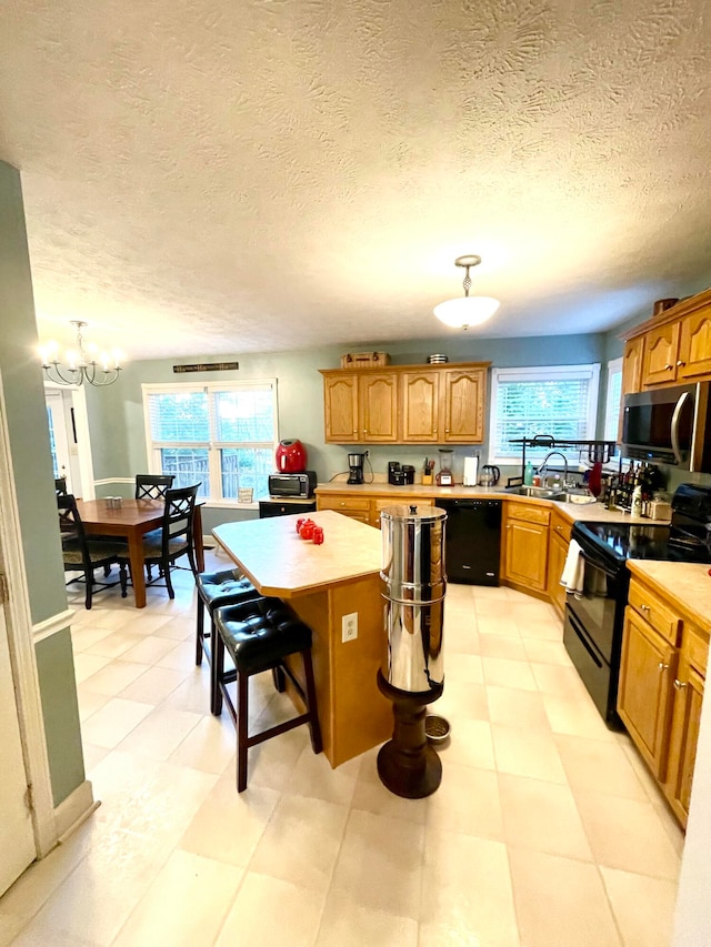 kitchen with a kitchen island, a breakfast bar area, a textured ceiling, and black appliances