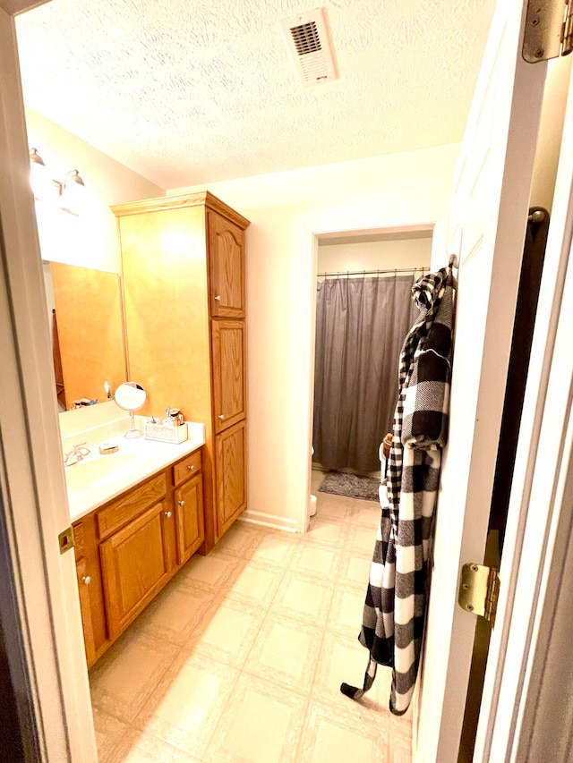 bathroom with a textured ceiling, vanity, and a shower with curtain