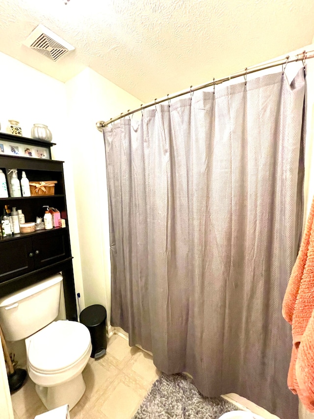 bathroom with a shower with curtain, toilet, and a textured ceiling