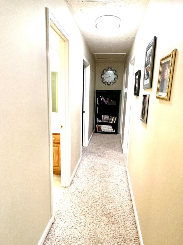 hall with light colored carpet and a textured ceiling