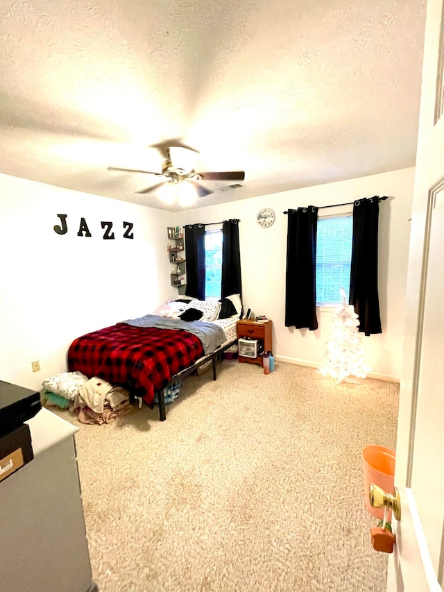 bedroom with ceiling fan, carpet, and a textured ceiling