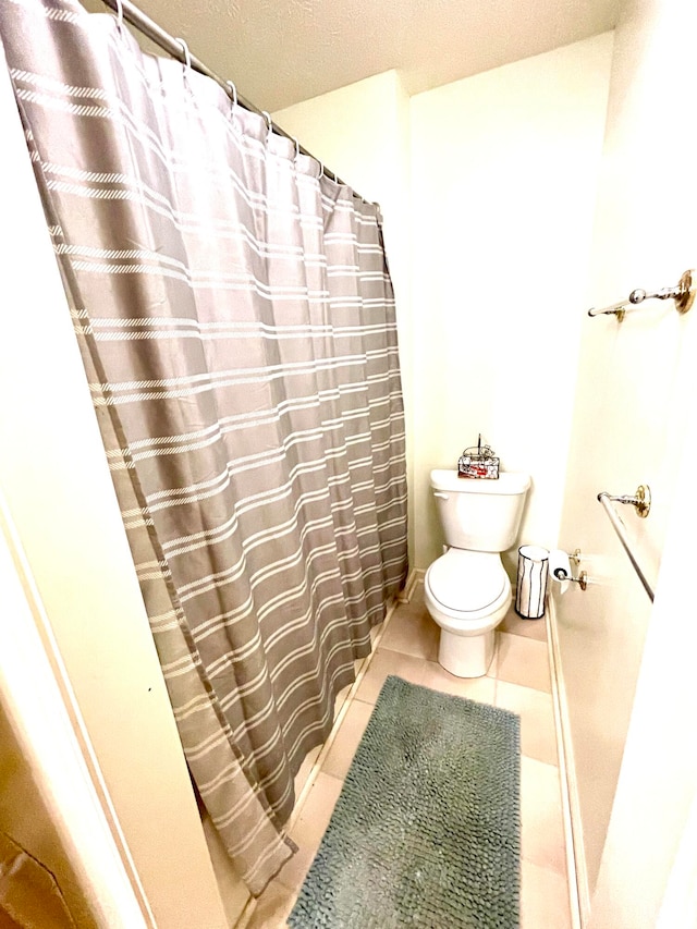 bathroom with walk in shower, tile patterned floors, a textured ceiling, and toilet