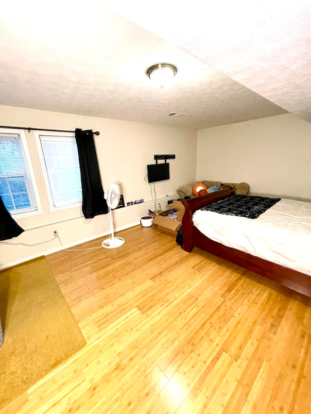 bedroom with wood-type flooring and a textured ceiling