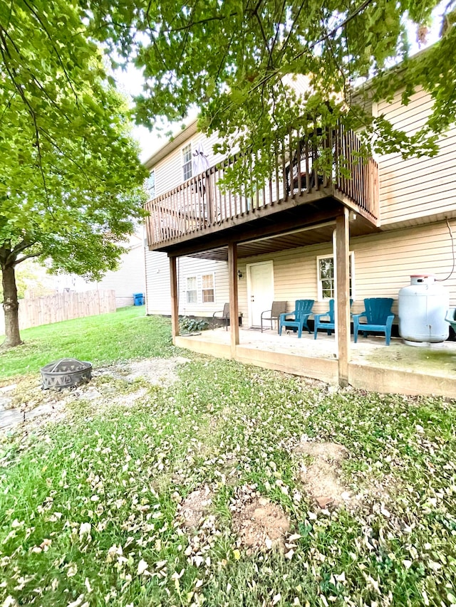 rear view of house featuring a wooden deck, a fire pit, and a patio area