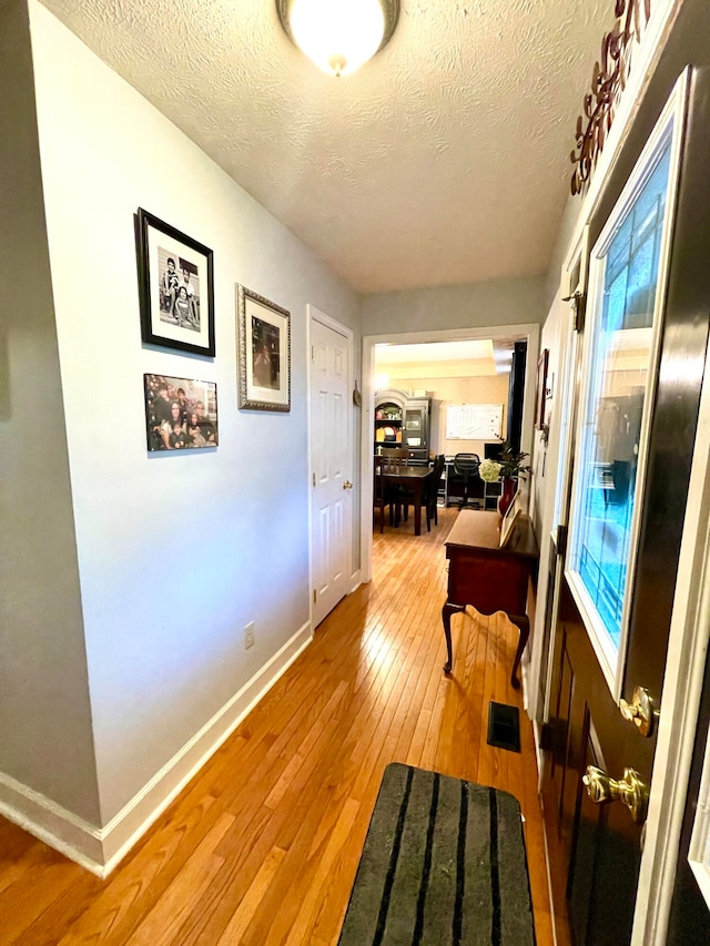 corridor featuring a textured ceiling and light hardwood / wood-style flooring