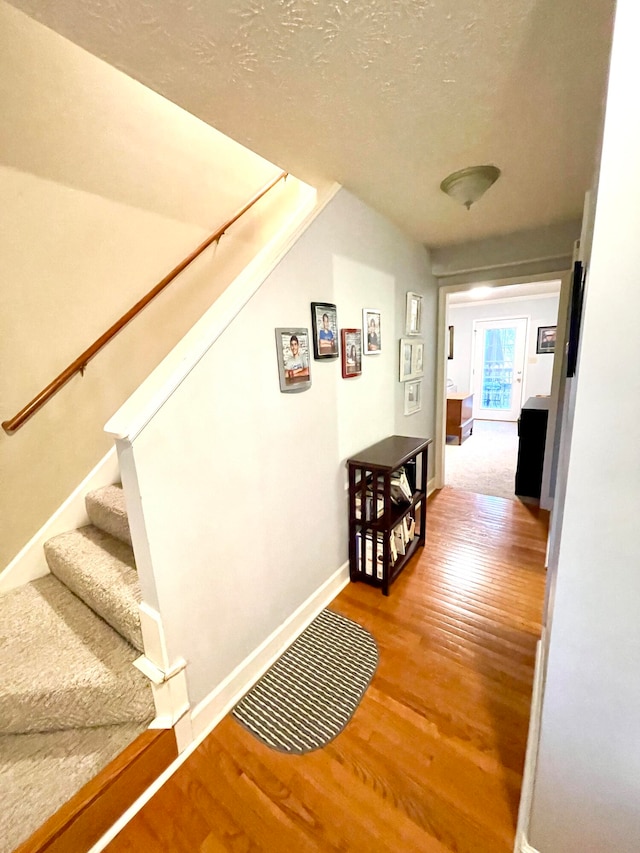 corridor with hardwood / wood-style floors and a textured ceiling