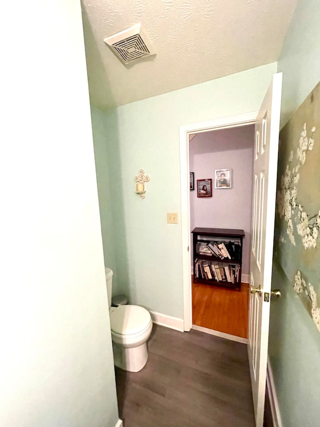 bathroom featuring a textured ceiling, hardwood / wood-style floors, and toilet