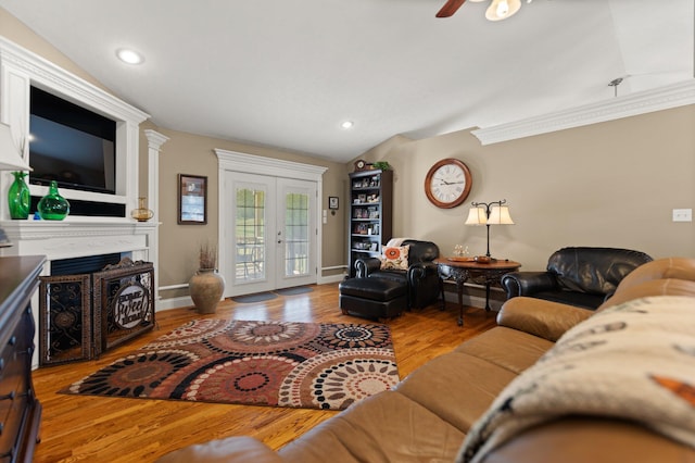 living room with french doors, light hardwood / wood-style flooring, crown molding, and vaulted ceiling