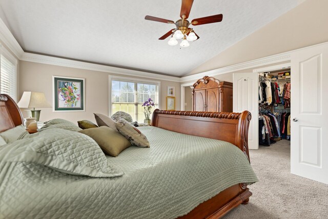 bedroom with lofted ceiling, ceiling fan, a closet, a walk in closet, and light colored carpet