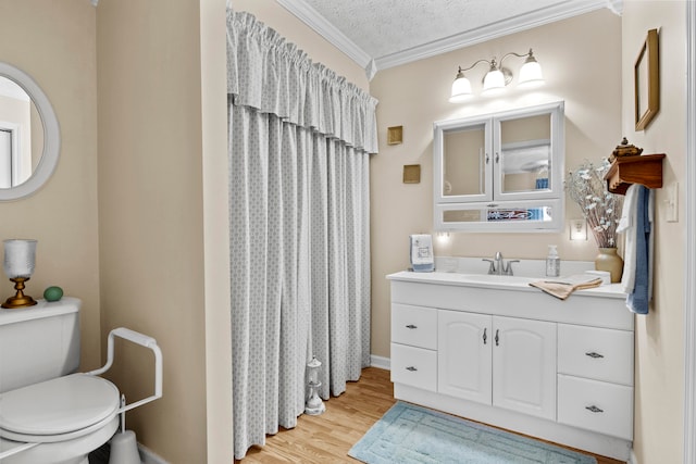 bathroom featuring vanity, wood-type flooring, a textured ceiling, crown molding, and toilet