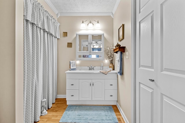 bathroom with wood-type flooring, vanity, crown molding, and a textured ceiling