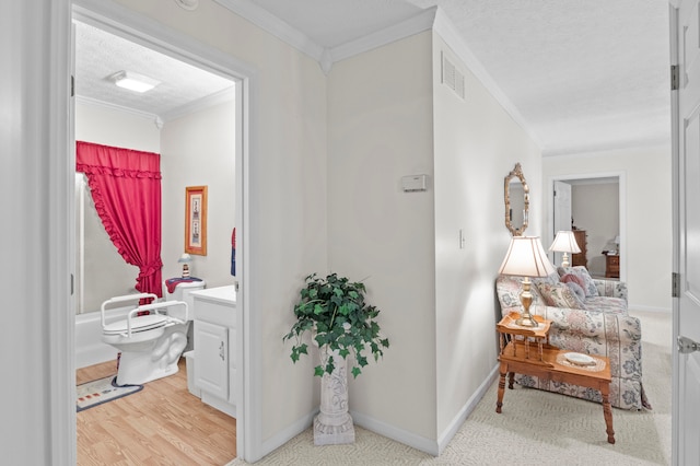 hall with a textured ceiling, light wood-type flooring, and crown molding