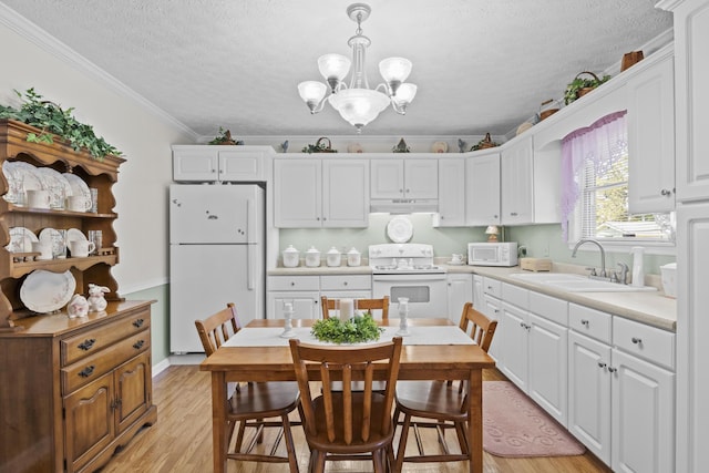 kitchen with a textured ceiling, under cabinet range hood, a sink, and white appliances