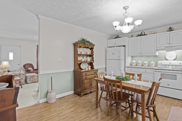 dining area featuring light wood finished floors, an inviting chandelier, ornamental molding, and visible vents
