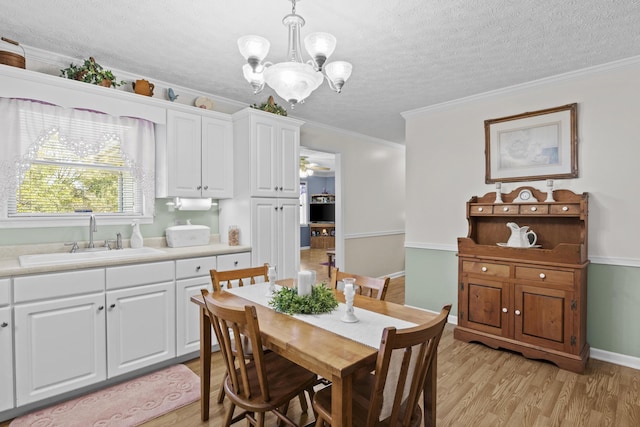 dining space featuring ornamental molding, light wood finished floors, a chandelier, and a textured ceiling