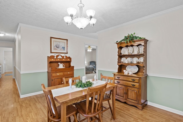 dining area featuring ceiling fan with notable chandelier, crown molding, light hardwood / wood-style flooring, and a textured ceiling