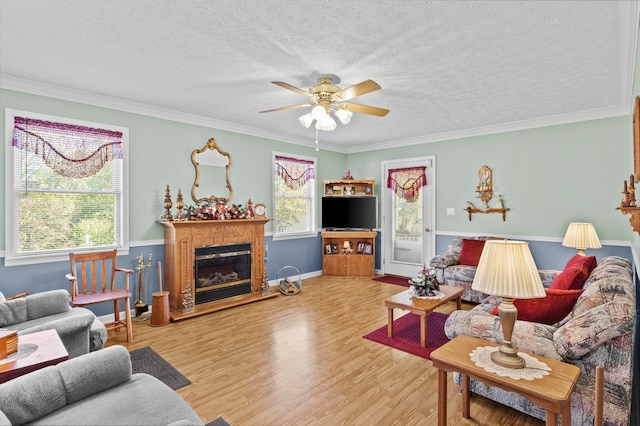 living room with ornamental molding, hardwood / wood-style flooring, ceiling fan, and a textured ceiling