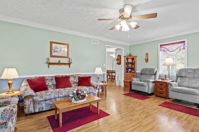 living room featuring ornamental molding, ceiling fan with notable chandelier, light hardwood / wood-style floors, and a textured ceiling