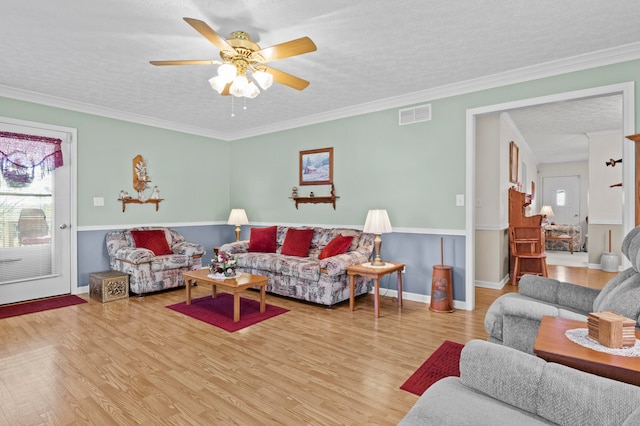 living room featuring ceiling fan, a textured ceiling, light hardwood / wood-style flooring, and ornamental molding