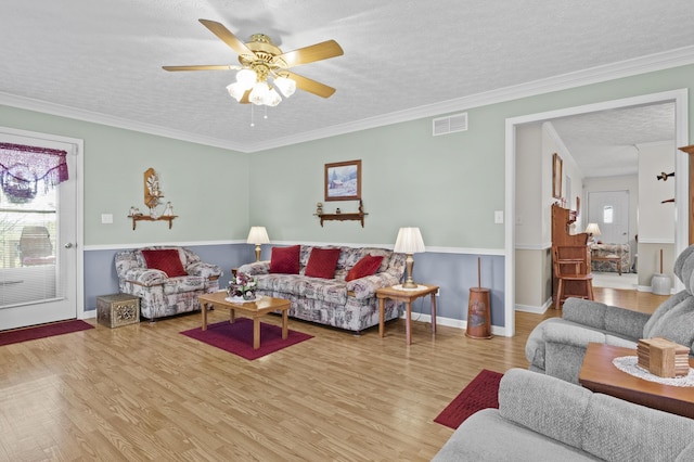 living area featuring visible vents, baseboards, a ceiling fan, a textured ceiling, and wood finished floors