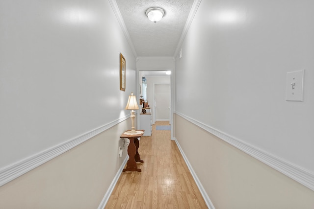 hallway featuring crown molding, light hardwood / wood-style floors, and a textured ceiling