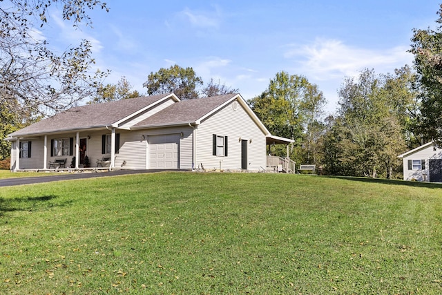 view of front of house featuring a porch, a shingled roof, a garage, and a front yard