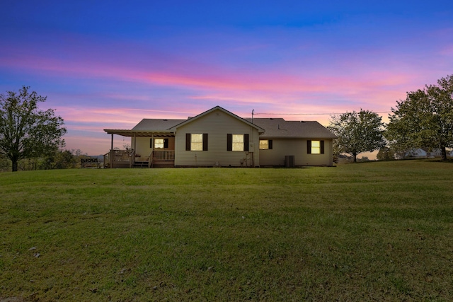 back of house at dusk with central AC and a lawn