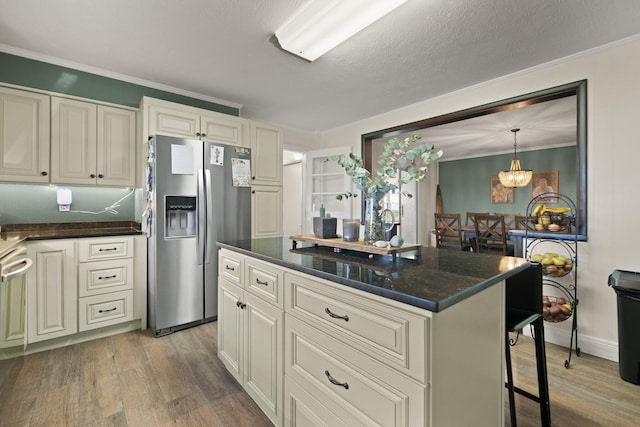 kitchen with ornamental molding, wood-type flooring, a textured ceiling, stainless steel refrigerator with ice dispenser, and a center island