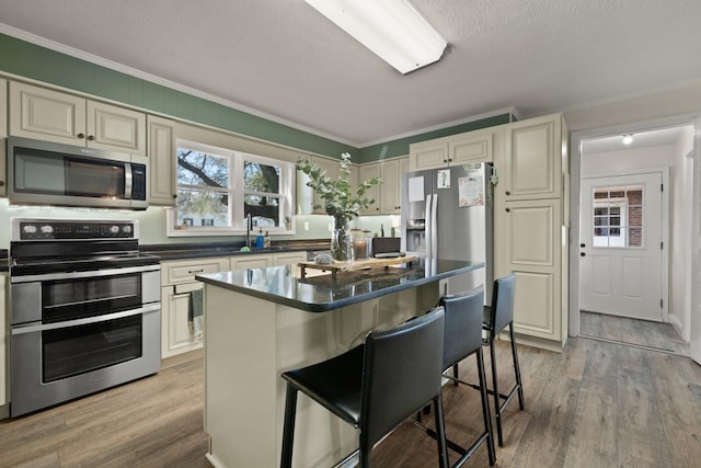 kitchen with ornamental molding, light hardwood / wood-style floors, a breakfast bar area, and stainless steel appliances