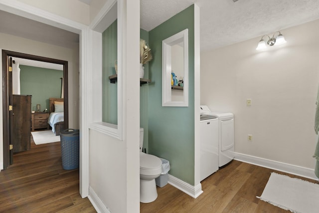 bathroom featuring hardwood / wood-style flooring, a textured ceiling, toilet, and washing machine and dryer