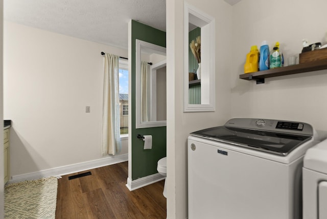 laundry area with a textured ceiling, washing machine and dryer, and dark hardwood / wood-style flooring