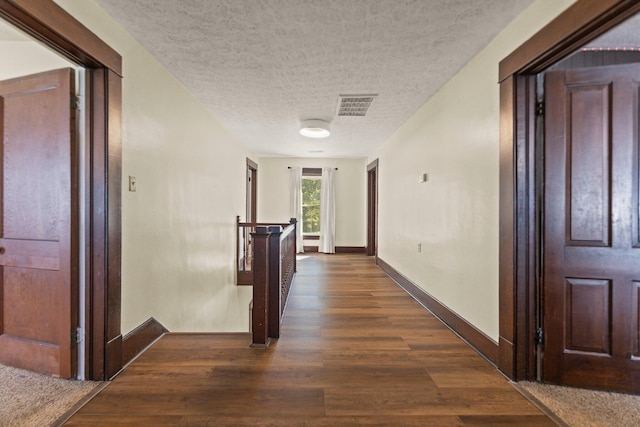 hall with a textured ceiling and dark wood-type flooring