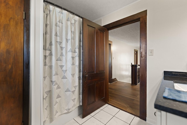 bathroom featuring vanity, wood-type flooring, a shower with shower curtain, crown molding, and a textured ceiling