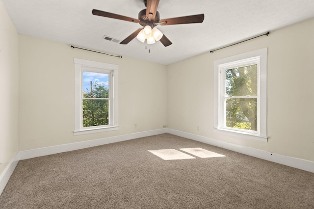 carpeted spare room featuring ceiling fan and a wealth of natural light