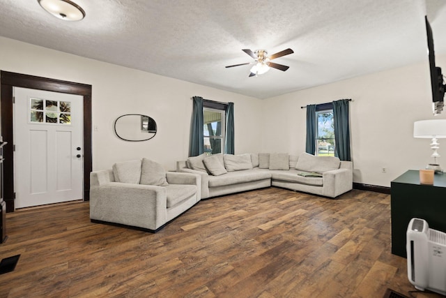 living room featuring ceiling fan, dark hardwood / wood-style floors, and a textured ceiling